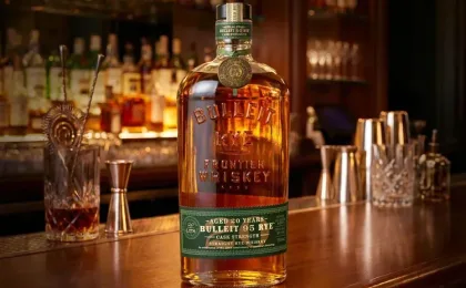 Bottle of Bulleit Frontier Whiskey beside a glass of rye whiskey