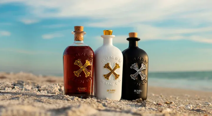 Bumbu : comprendre sa catégorie et son étiquetage Les trois types de bouteilles de la famille Bumbu sur une plage des Caraïbes
