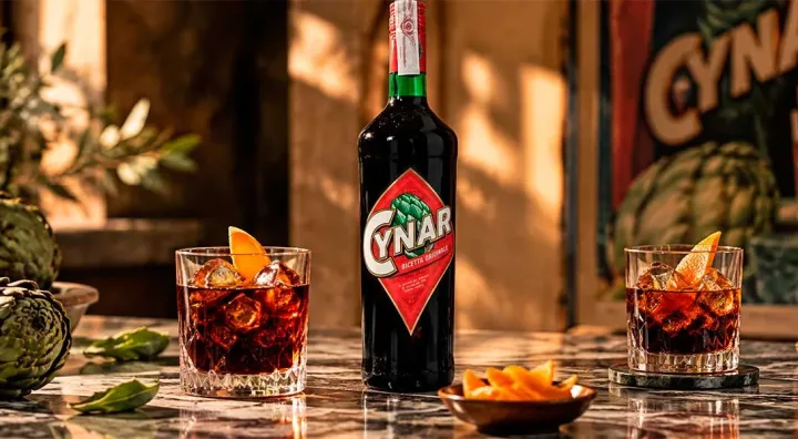 Cynar servido como aperitivo italiano Copa con Cynar servido con hielo junto a alcachofas y piel de cítrico