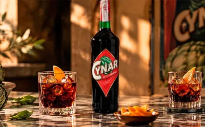 Copa con Cynar servido con hielo junto a alcachofas y piel de cítrico