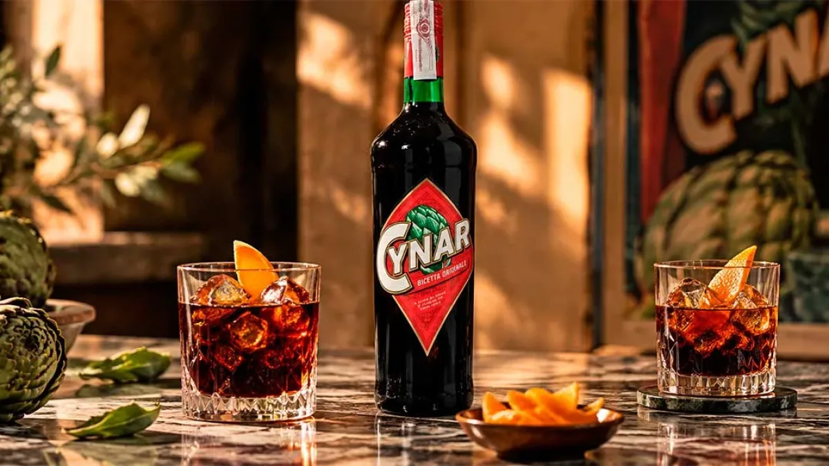 Glass of Cynar served over ice with artichokes and citrus peel nearby