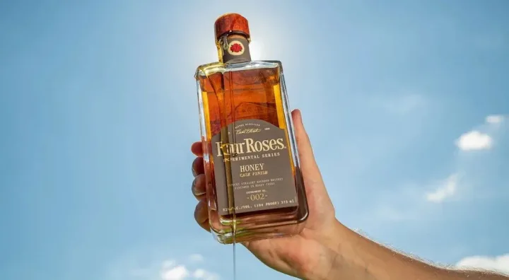 Four Roses Honey Cask Finish, Experimental Series No. 002 Bouteille de bourbon Four Roses aux côtés d’un miel vieilli en fût de bourbon