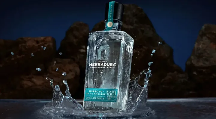 Botella de tequila blanco Herradura junto a agaves azules en Jalisco