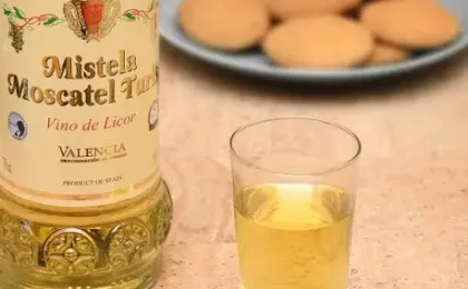 Glass of sweet mistela beside grapes and traditional aromas