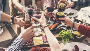 Une table avec des convives qui trinquent avec leurs verres de vin