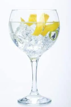 Hohes Kristallglas mit Eis, Gin, Tonic und Zitrone
